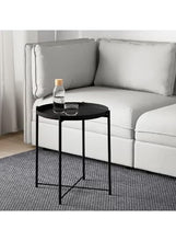 Round black side table with round top and three legs holding bottle