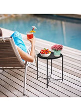 Round black side table with tray top holding drinks and a potted plant