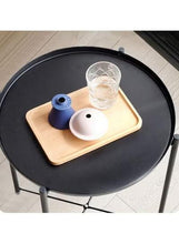 Black round side table with tan serving tray insert and three legs