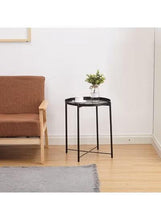 Round black side table with tray top and three slender legs