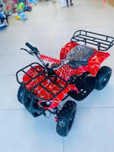 Red electric ATV quad bike with carry rack and gray seat, angled showroom view