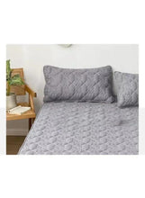 Dark grey fitted bedding topper with quilted pillowcases on a bed