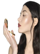 GUCCI glow highlighter compact held near face, frosted lilac-pearl finish