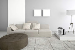White compact vertical fan heater standing on the floor in a room