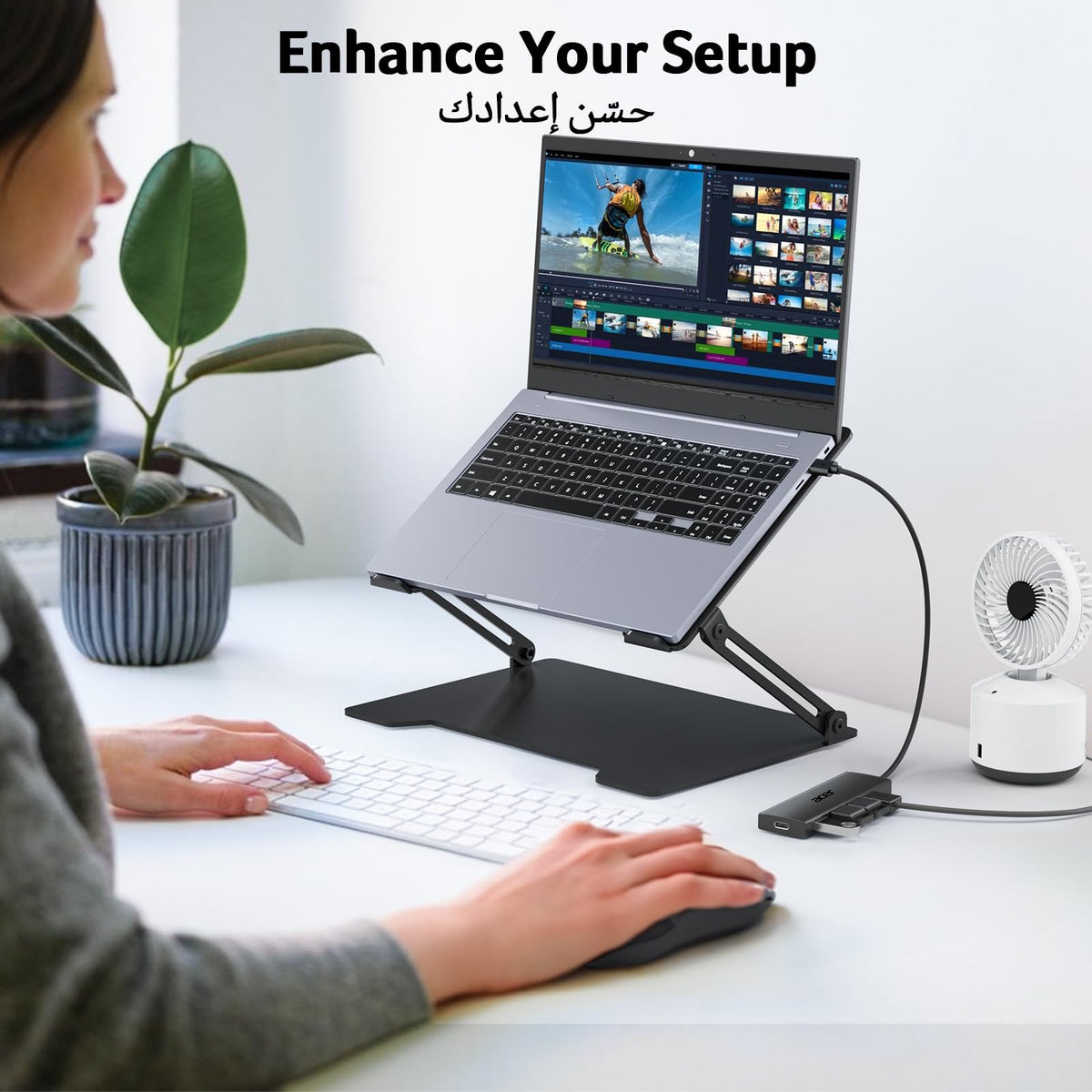 Laptop on adjustable stand connected to powered USB splitter for PC on white desk setup