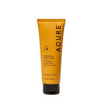Golden-yellow Acure brightening facial scrub tube with black base, shown front view.