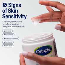 Moisturizing cream tub held in hands, with a dollop of cream on fingers