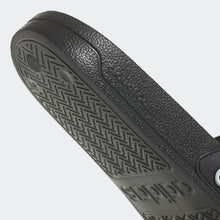 Black adidas slide sandal outsole with textured tread and brand logo embossing