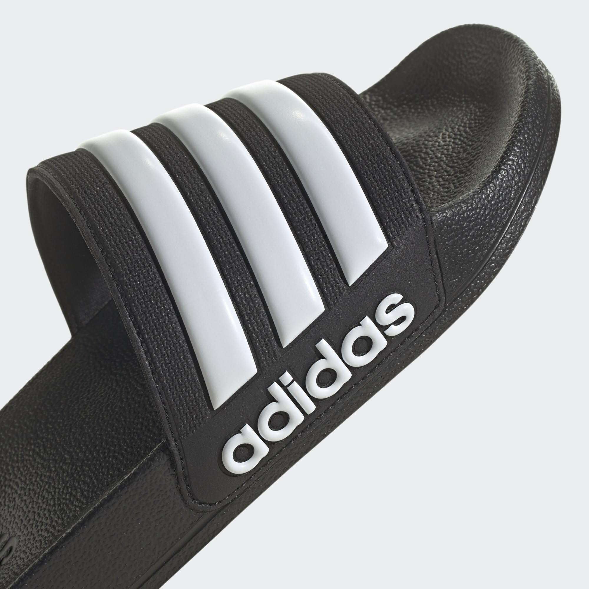 Black adidas pool slippers for men and women with white three stripes and textured footbed
