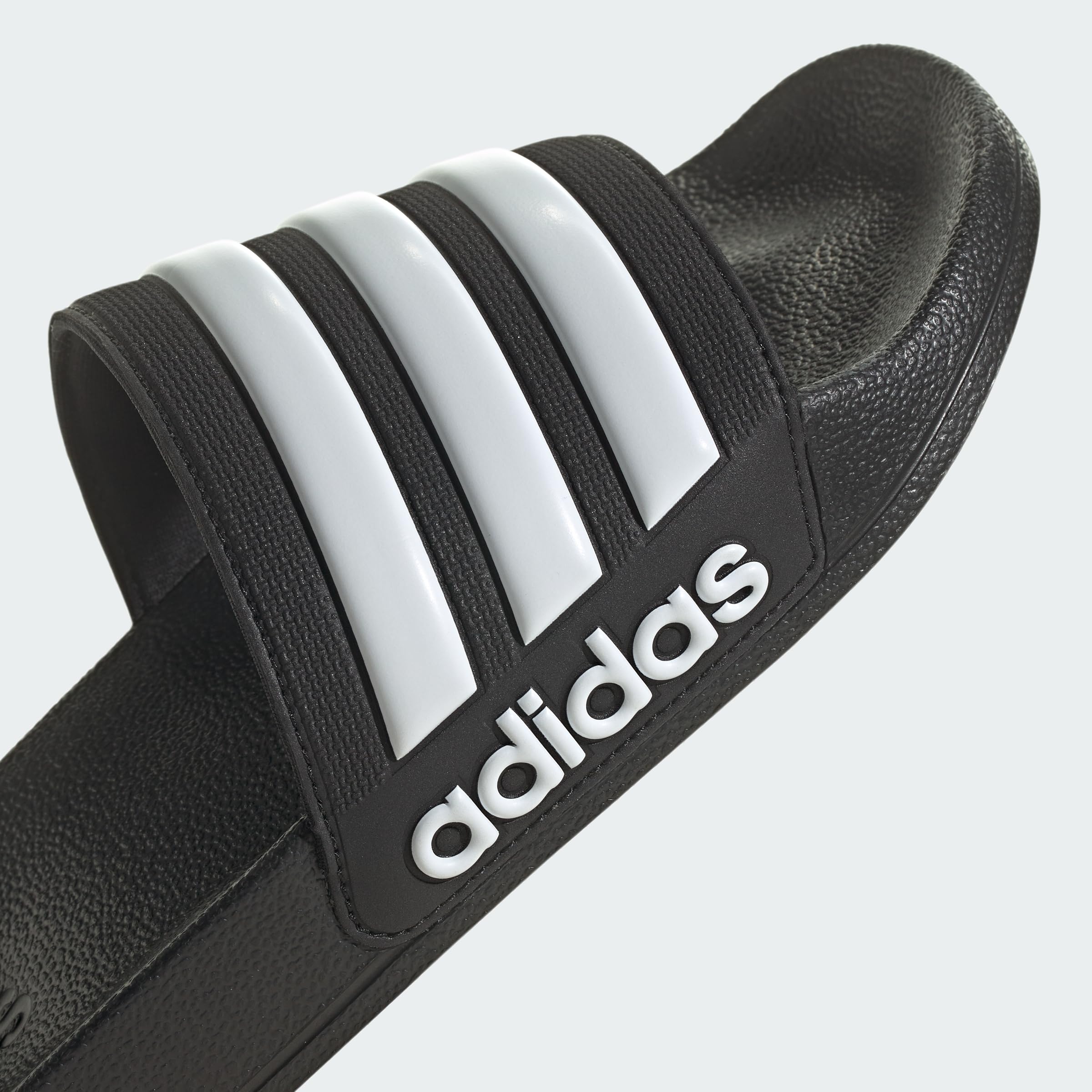Black adidas pool slippers for men and women with white brand stripes and logo