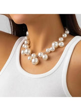 Pearl necklace worn on neckline with clustered round white beads and silver-tone links