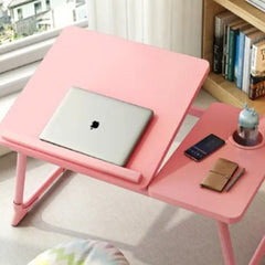Pink adjustable wooden laptop desk with tilted surface and side compartment holding phone and notebook