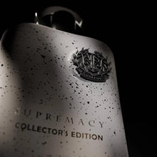 Close-up perfume bottle front with dark emblem, speckled light-gray finish