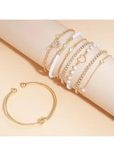 Stacked gold-tone bangles with pearl-bead bracelets and a thin open cuff