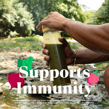 Hand holding a green greens supplement shake bottle