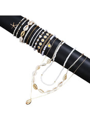 Huitich 14 piece layered beach jewelry with shells, beads, and gold accents on black display