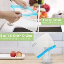 Clear reusable snack bag with light blue zip seal, being held over a kitchen sink