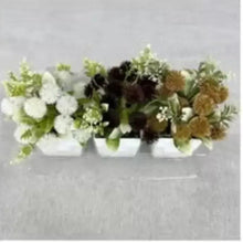 Artificial floral bouquet in white planter with dark blooms, brown petals, and greenery