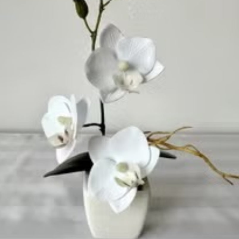 White artificial flowers in pot by Huitich with realistic petals and green stems on table