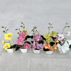 Huitich white artificial flowers in pot among colorful artificial flower arrangements in small white pots