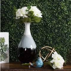 Huitich artificial grass wall backdrop with decorative white flowers, blue bird figurine, and wooden table accents