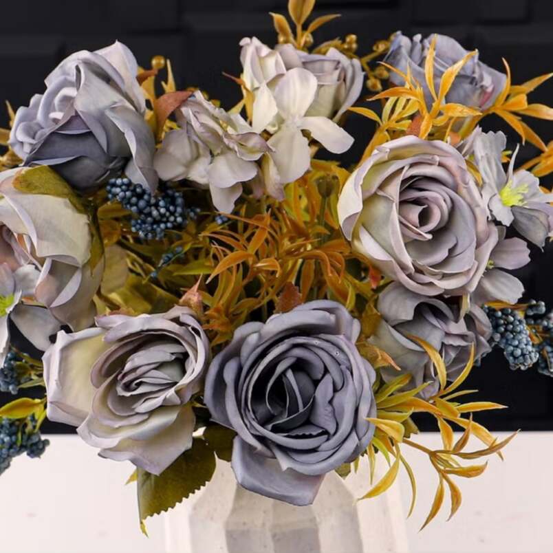 Huitich artificial mini rose flower bunch in muted purple shades with green and yellow foliage in a white vase
