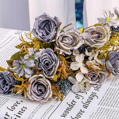 Huitich artificial mini rose flower bunch with gray and white roses and green leaves on newspaper background