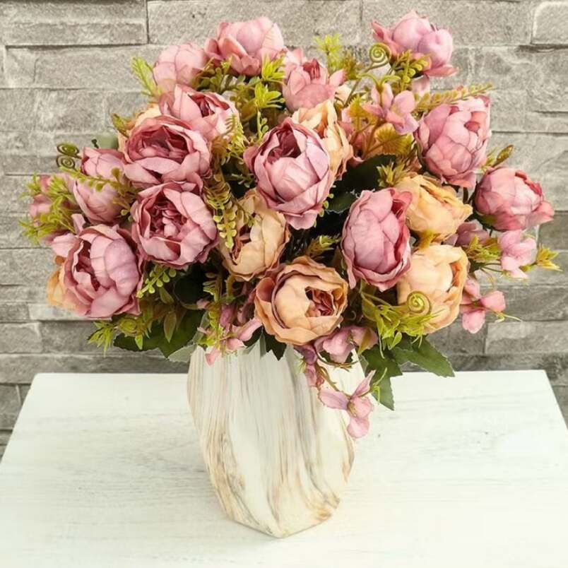 Huitich artificial pink peony bouquet in a marbled vase with green foliage on white table