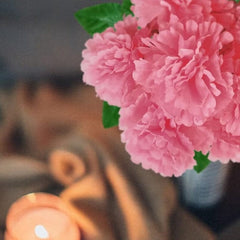 Huitich artificial pink peony flowers in silk with green leaves displayed near a candle