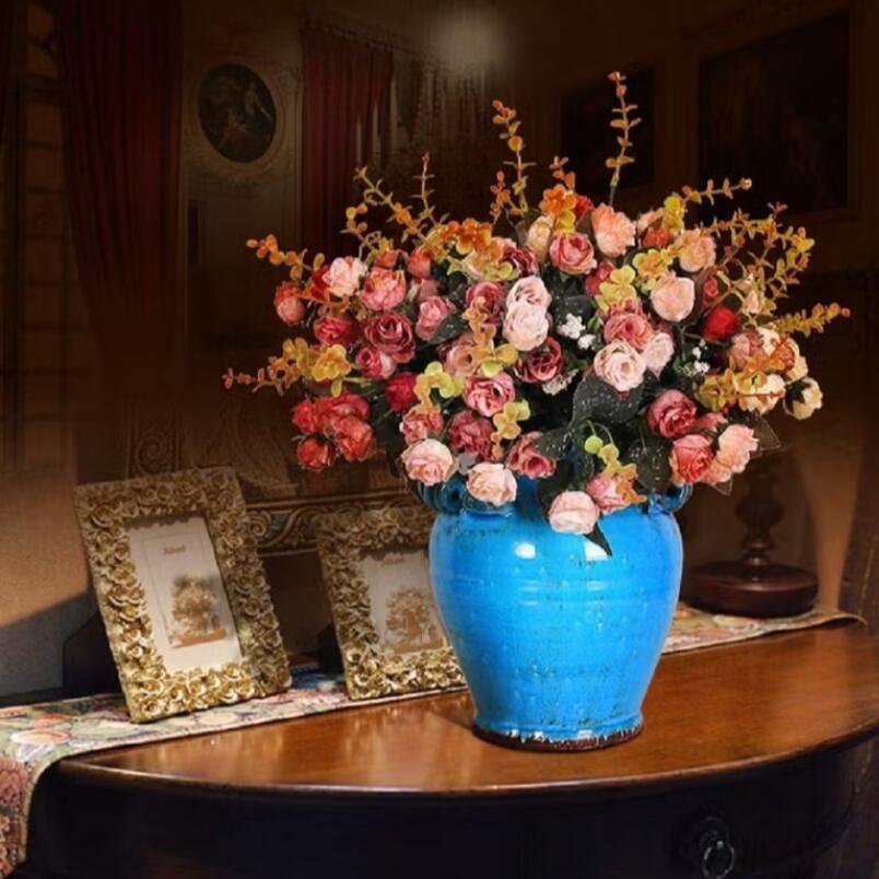 Huitich artificial pink rose bouquet in a blue vase displayed on a wooden table with decorative photo frames