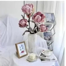Artificial pinkish purple rose bouquet in a white vase with slender stems