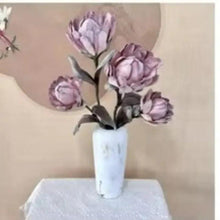 Artificial pinkish purple flower bouquet in a white vase on a display table
