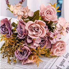 Huitich artificial rose flower bunch in soft pink and purple tones with green foliage on newspaper