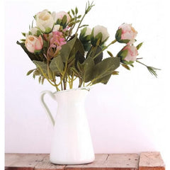 Huitich artificial rose flower bunch in white pitcher vase with green leaves on wooden surface