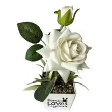 Artificial white rose in small white pot with green leaves and buds