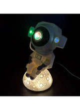 White astronaut night light with green and blue glowing headlamp on base