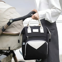 Huitich stylish black and white baby backpack for moms hanging on stroller handle with woman standing nearby