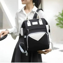 Black baby backpack with white handles, front pocket and triangular insulated front panel