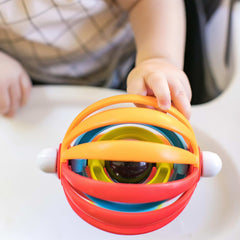 Baby hand reaching for colorful spherical rattle on high chair tray baby high chair activity toy for sensory play