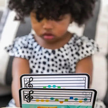 Child playing a wooden music toy piano with tablet screens in view