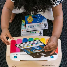 Wooden music toy piano with tablet screen held over colorful keys by a child