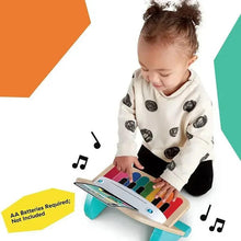 Wooden music toy piano with rainbow keys and tablet, being pressed by a child’s hands