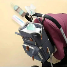 Gray diaper bag attached to stroller with open top organizer and tan zipper pulls