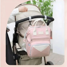 Pink baby travel backpack attached to stroller, front zipper pocket visible
