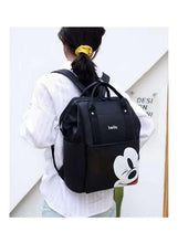 Black baby travel bag viewed from back, with cartoon face pocket and top handle straps