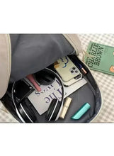 Open grey bag interior with phone, wipes, bottles, and other baby items