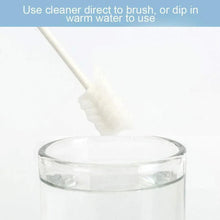 Baby tongue cleaner brush dipped in clear water cup, white textured head