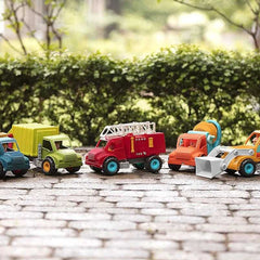 Colorful Battat dump truck toy for kids lined up on a cobblestone surface with greenery background
