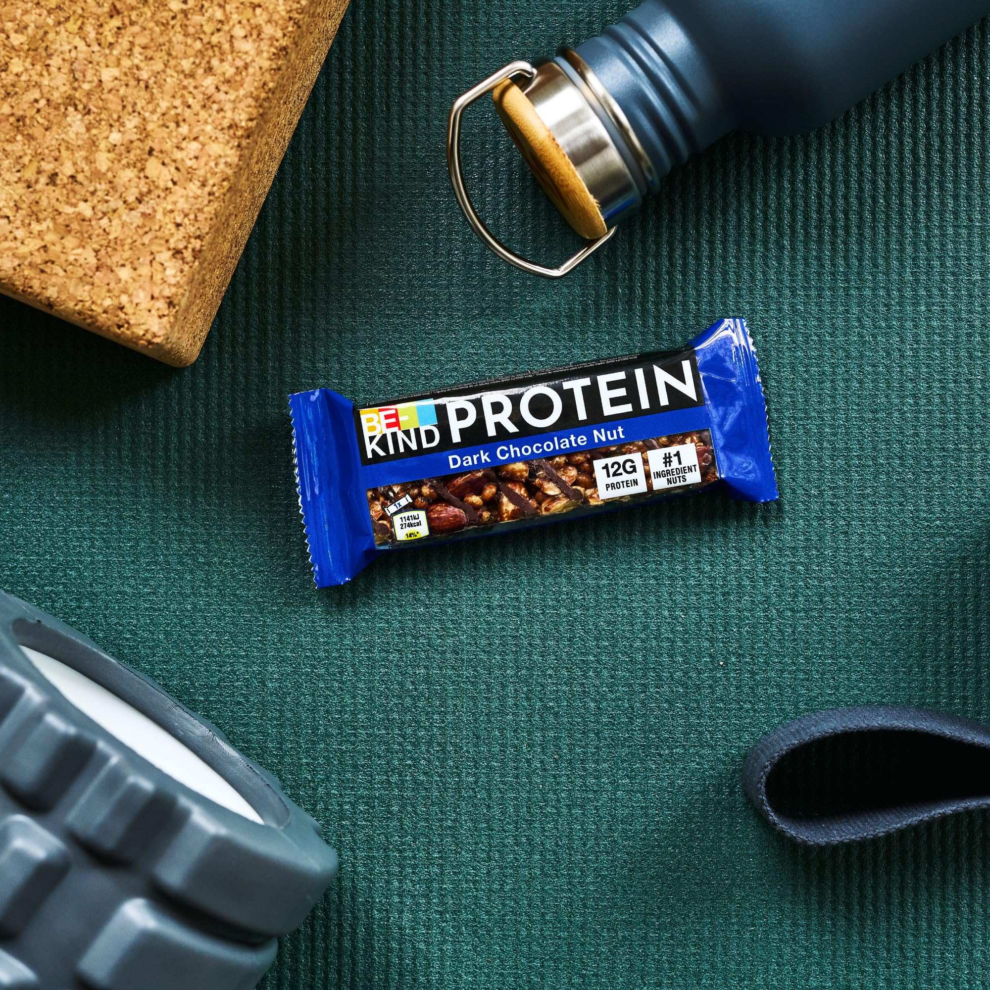BE KIND dark chocolate protein bars on green workout mat with water bottle and foam roller
