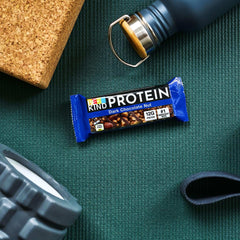 BE KIND dark chocolate protein bars on green workout mat with water bottle and foam roller